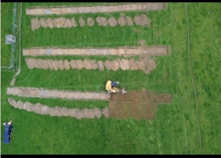 Aerial view of parallel archaeological test trenches being excavated