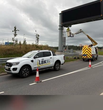 LBK pickup and cherry picker under traffic management beside an overhead motorway gantry